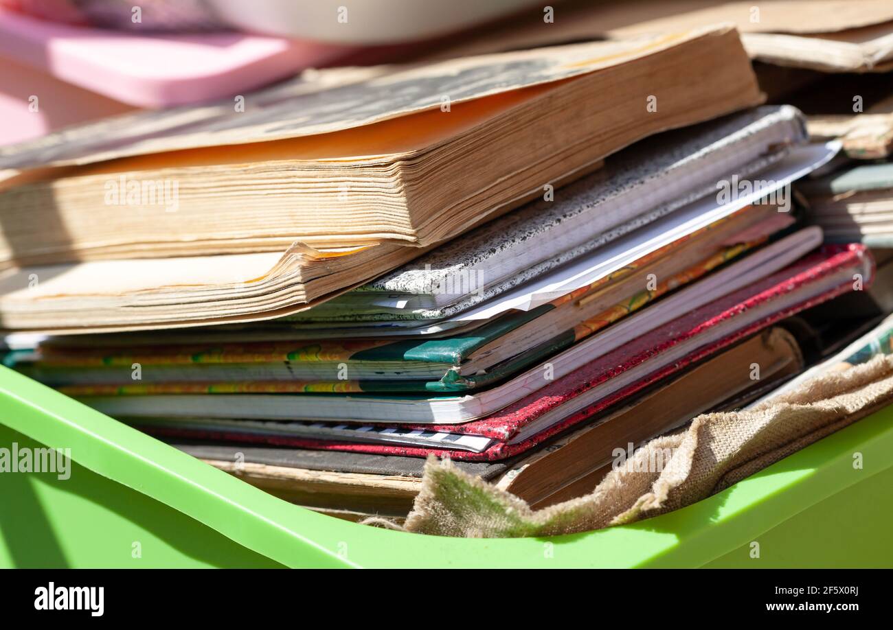 Muchos libros viejos y cuadernos de papel diferentes en un contenedor fuera  en la luz del sol, pila. Caja llena de literatura vieja, regalando libros  usados. Libro fa Fotografía de stock -