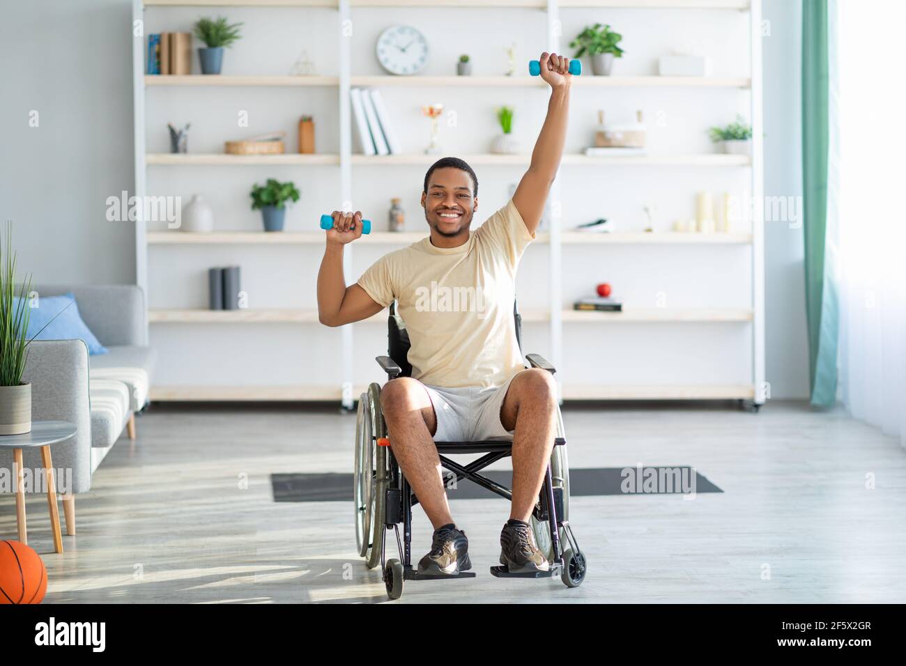 Hombre discapacitado sentado en una silla de ruedas, haciendo un ejercicio  con una pelota pilates más pequeña en el centro de rehabilitación  fisioterapéutica Fotografía de stock - Alamy
