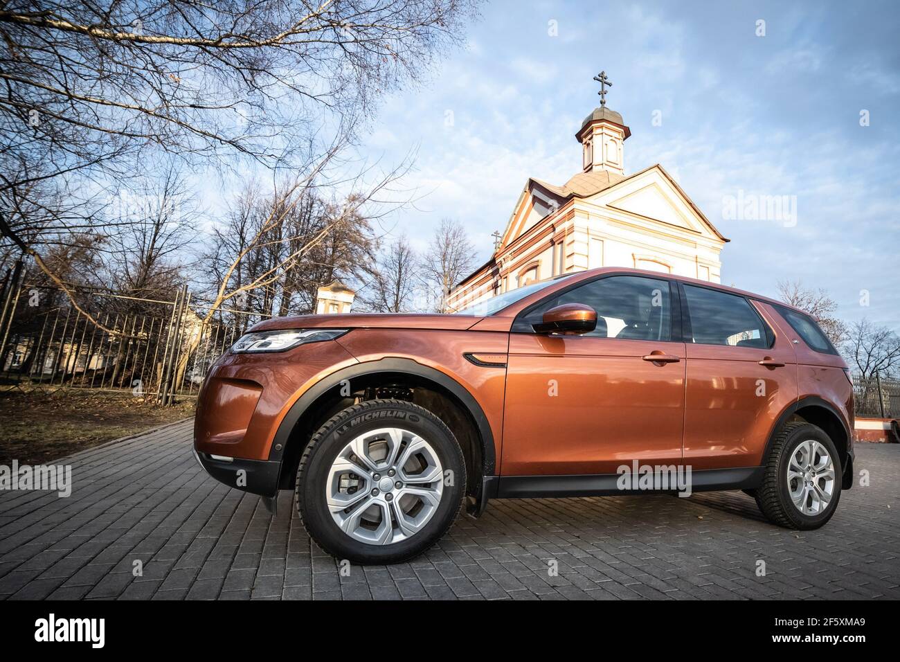 Moscú, Rusia - 20 de diciembre de 2019: Vista lateral de todos los nuevos suv premium de inglaterra. Land rover Discovery Sport estacionado cerca de chirsh. Coche naranja con tracción total en el suelo. Foto de stock