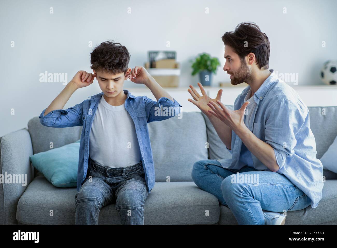 Violencia de los padres. Papá enojado regañando a su hijo inocente, que  cubría oídos para no escuchar a su padre enojado Fotografía de stock - Alamy