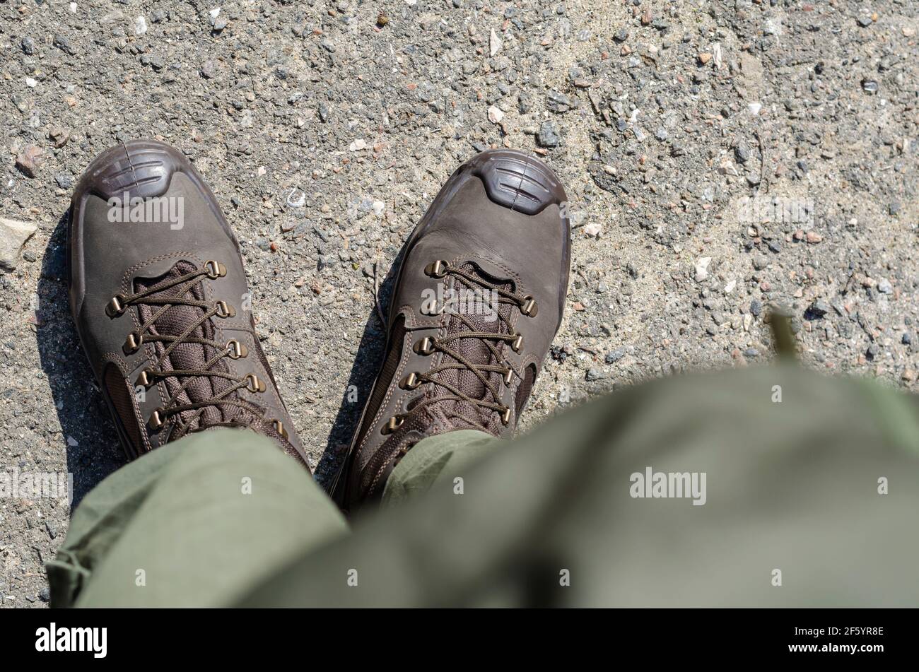 Piernas en botas militares marrones y pantalones verdes. Soldado parado en  uniforme en el pavimento exterior. Vista desde arriba en ángulo Fotografía  de stock - Alamy
