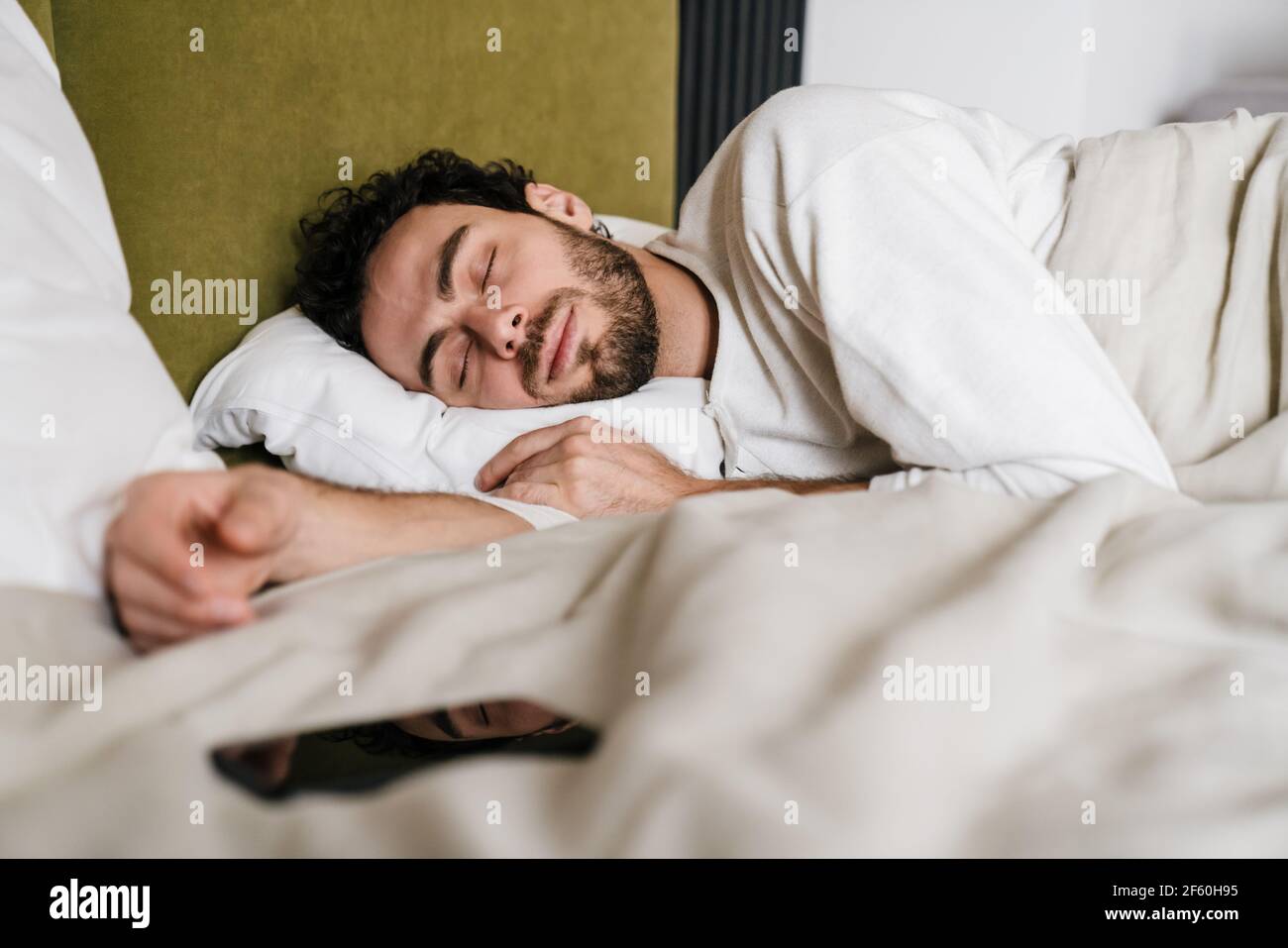 Hombre tranquilo durmiendo con teléfono móvil mientras está acostado en la  cama Fotografía de stock - Alamy