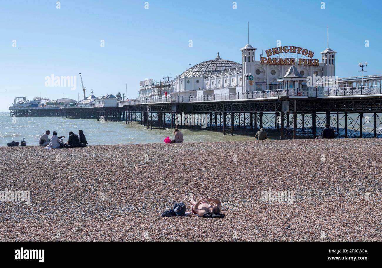 Brighton Reino Unido 29th de marzo de 2021 - UNA tumbona disfruta de un hermoso día soleado en la playa de Brighton ya que las restricciones de cierre han comenzado a disminuir en Inglaterra se espera que las temperaturas alcancen los mediados de 20s en algunas partes del sudeste durante los próximos días. : crédito Simon Dack / Alamy Live News Foto de stock