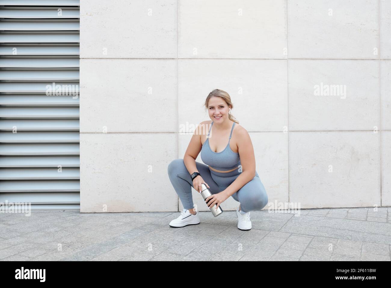 Feliz muy joven ajuste más tamaño joven mujer descansando después entrenamiento y agua potable Foto de stock