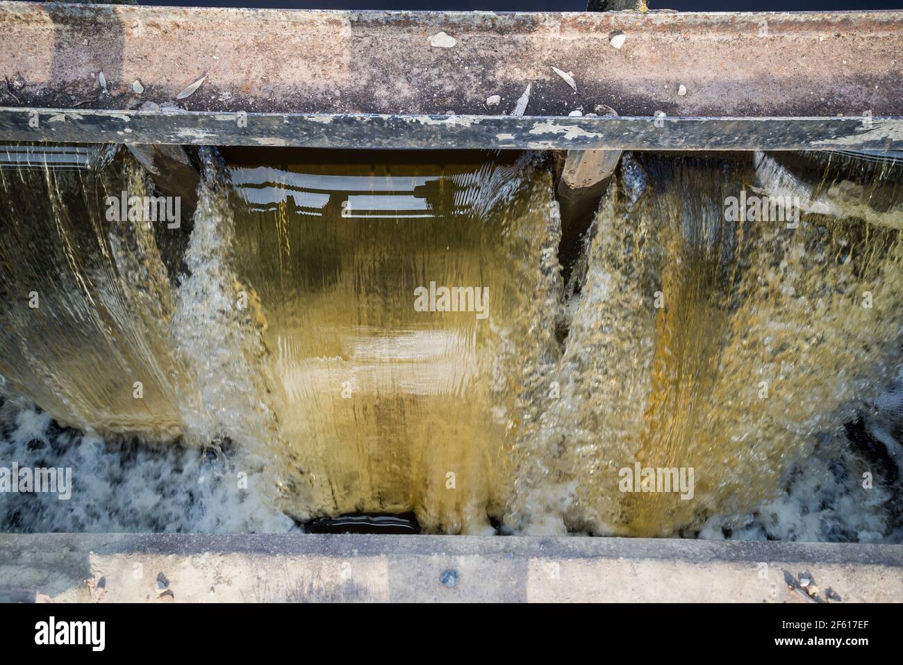 El agua que fluye rápidamente se bloquea en un día de primavera. El agua forma espuma. Un cálido día de primavera Foto de stock