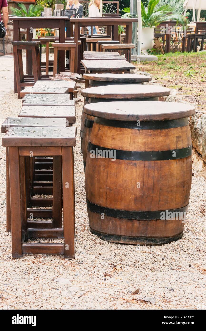 un barril de vino de madera y metal utilizado como una mesa en la cubierta  de madera del café. Un montón de barriles de madera a lo largo de la pared.  Terraza