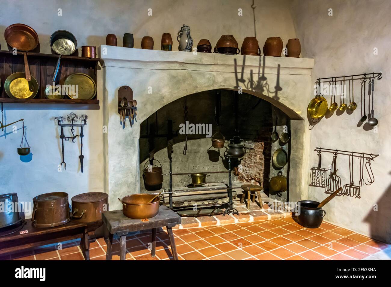 Interiores del Castillo de Bauska - cocina con latón del siglo 16th-17th, hierro y equipos de cocina de madera Foto de stock