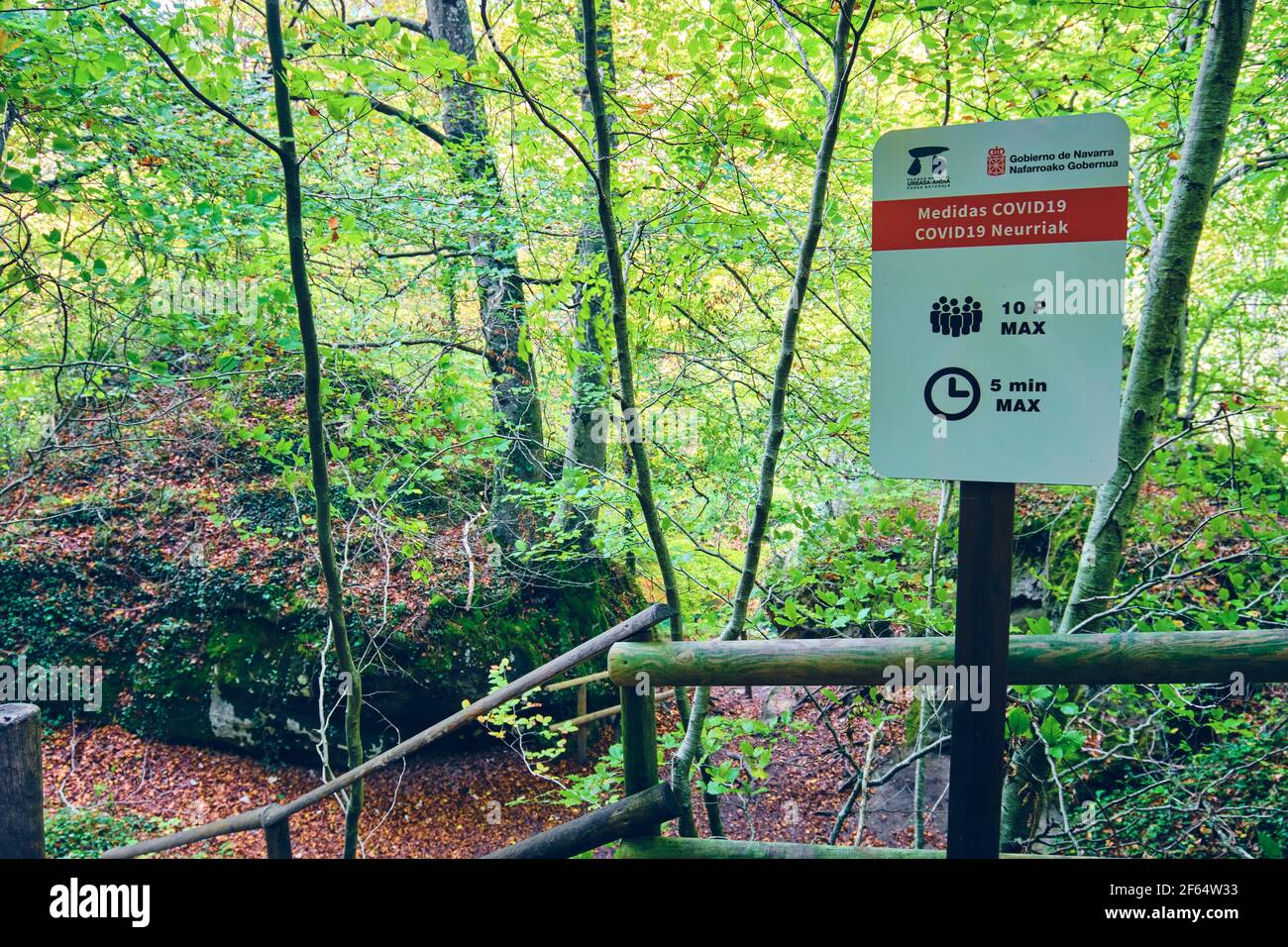 Señal con COVID 19 medidas cautelares en un lugar natural. Fuente del río Urederra. Foto de stock