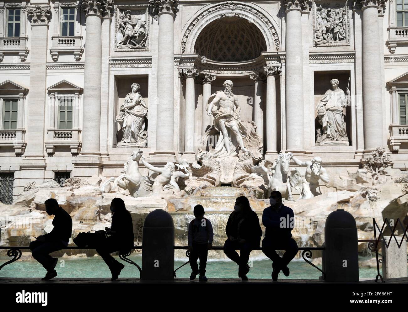 La gente se sienta frente a la Fontana de Trevi, ya que las restricciones COVID-19 en la región del Lacio son un poco relajadas, en Roma, Italia 30 de marzo de 2021. REUTERS/Yara Nardi Foto de stock