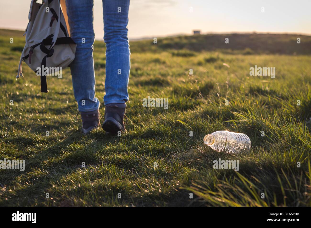 Contaminación del medio ambiente plástico. Hiker caminando lejos de la botella de plástico en la hierba. Personas irresponsables y conservación del medio ambiente Foto de stock
