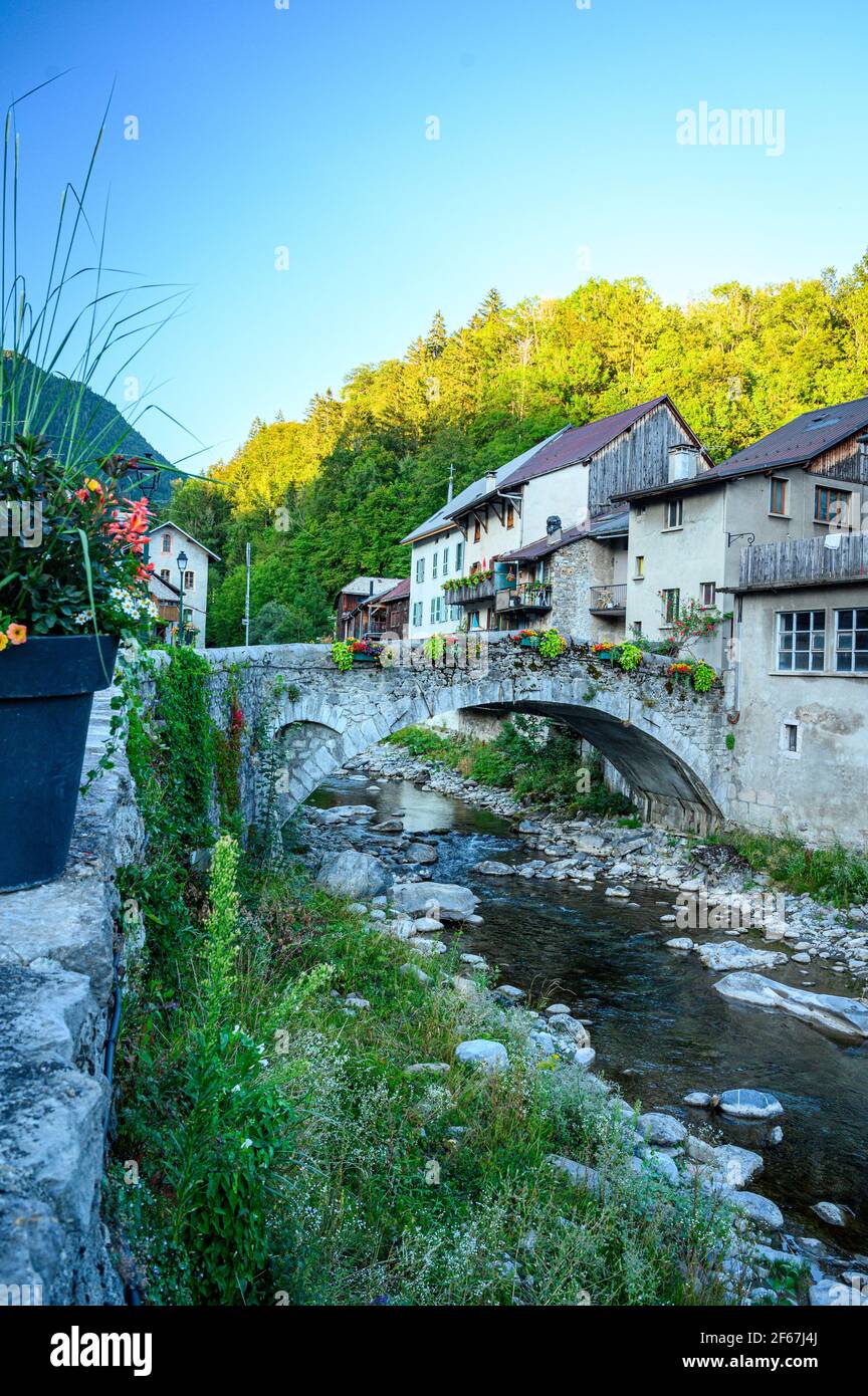 Antiguo puente de piedra arqueada sobre un pequeño arroyo en el pueblo de montaña. Belleza de la región montañosa de Giffre, Francia. Foto de stock