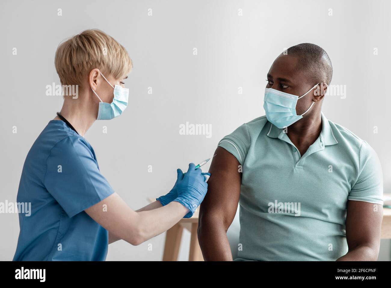 Vacunación, inmunización, prevención de enfermedades, hombre en máscara médica que recibe Covid-19 o vacuna contra la gripe Foto de stock