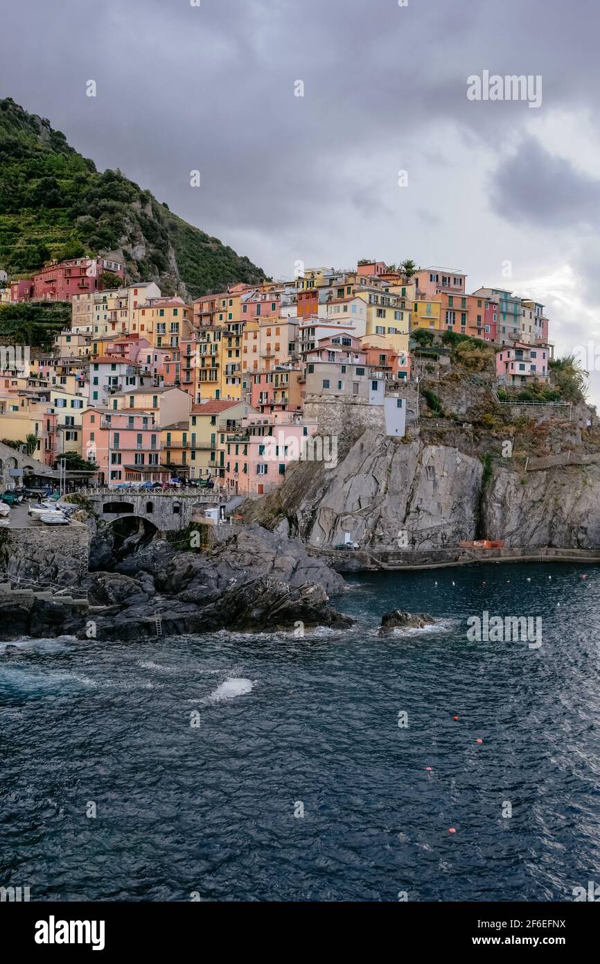 Vista clásica de Manarola, Cinque Terre, Italia - Colorful Houses en una formación de roca de acantilado espectacular cerca del mar con un puerto natural de pesca Foto de stock