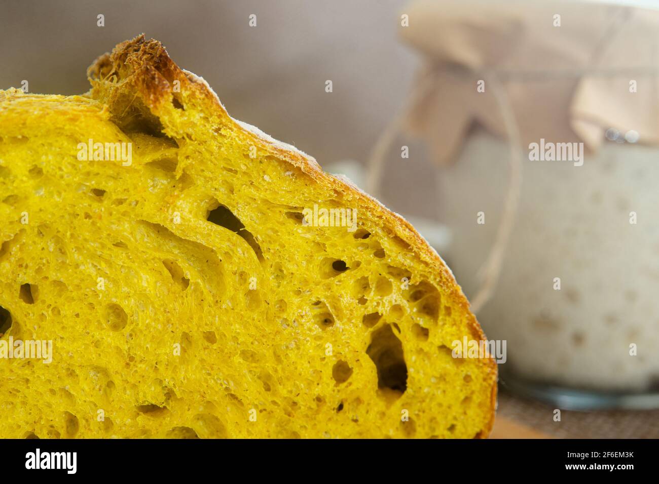 rebanada de pan de masa fermentada cúrcuma con el arrancador en el fondo Foto de stock