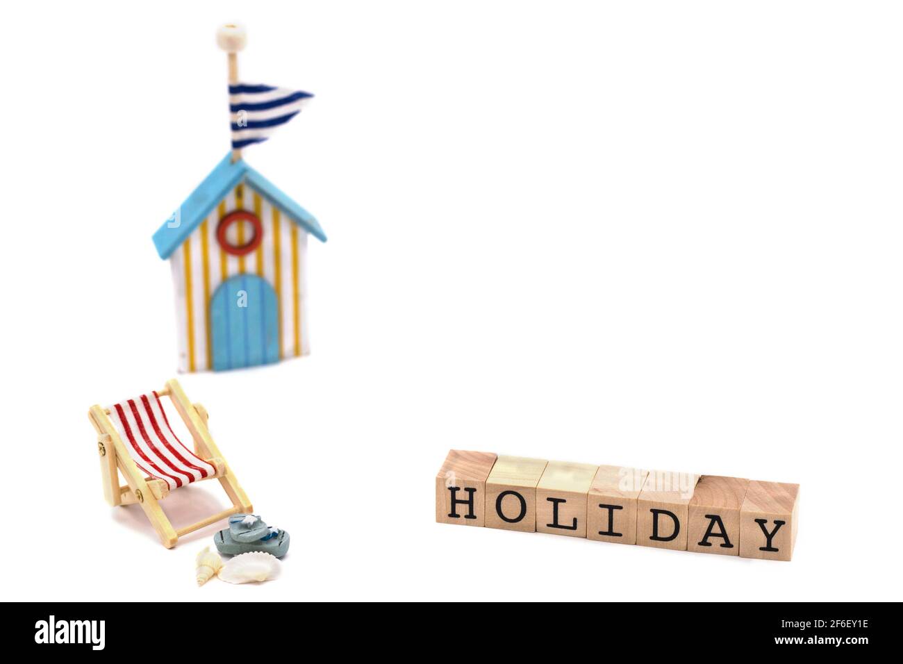 Silla de playa con sandalias, conchas, casa de baño, bloques de madera con texto de vacaciones Foto de stock