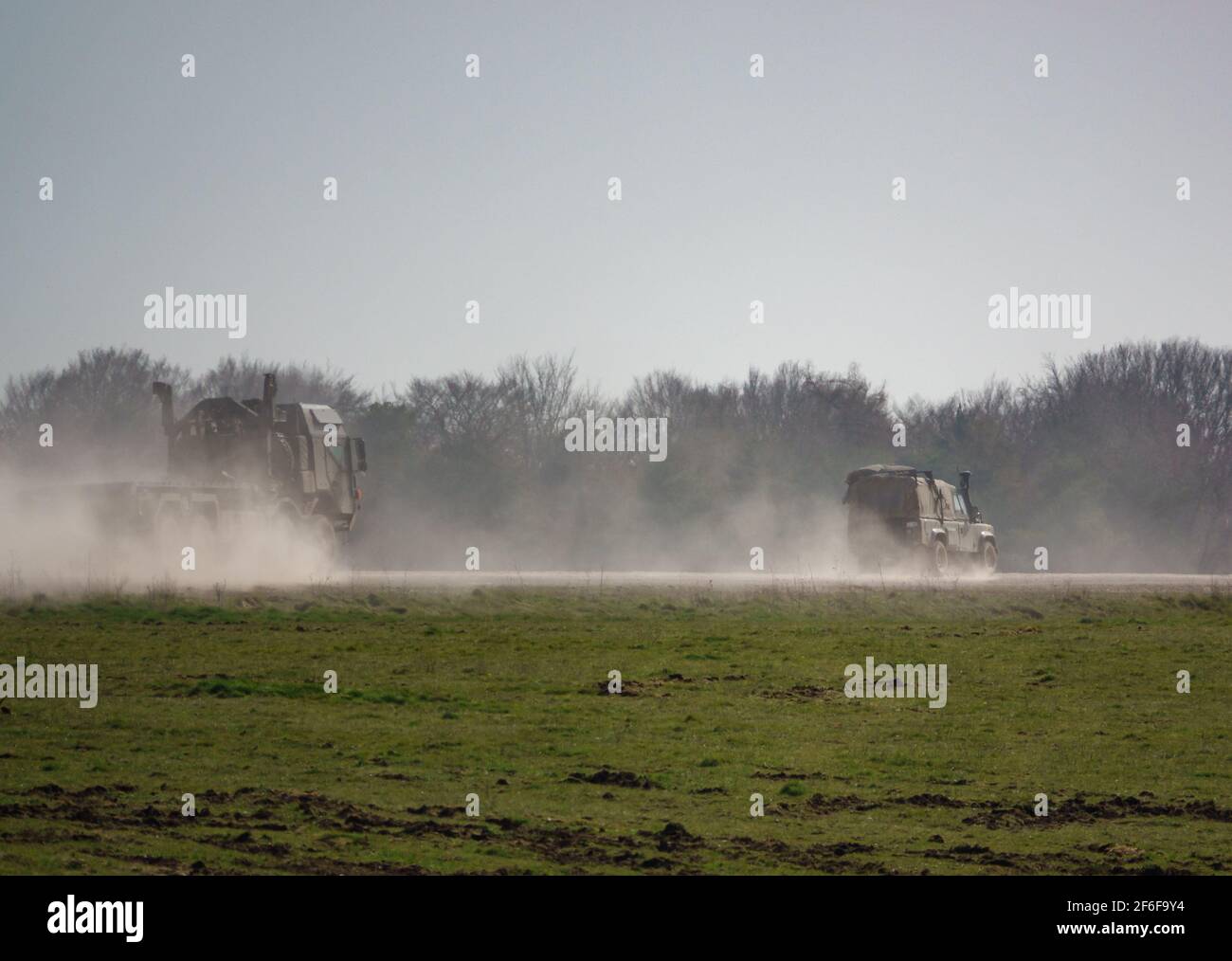 Un defensor del Land Rover del ejército británico y UN CAMIÓN SV 8X8 CONDUCEN a lo largo de una pista de piedra polvorienta, en maniobras Foto de stock