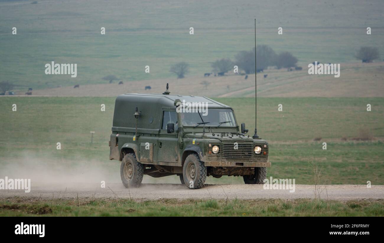 Un defensor del Land Rover del ejército británico que conduce por una pista de piedra polvorienta, en maniobras Foto de stock