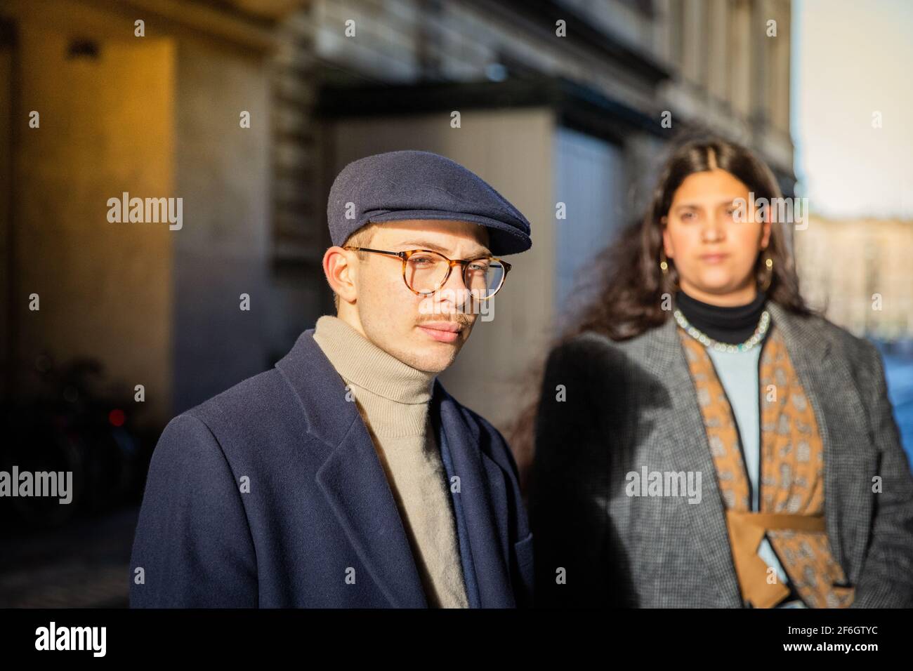 Retrato de un chico joven serio y elegante con una gorra plana. Su amigo está fuera de foco detrás. Concepto de juventud y diversidad Foto de stock