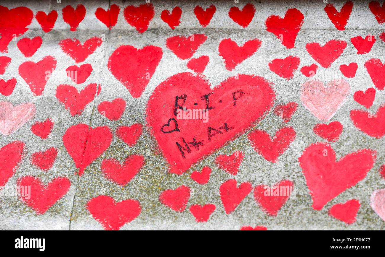 (210401) -- LONDRES, 1 de abril de 2021 (Xinhua) -- Foto tomada el 31 de marzo de 2021 muestra mensajes y corazones rojos que representan a las víctimas que murieron de COVID-19 en el Muro Conmemorativo Nacional del COVID en las afueras del Hospital St Thomas en Londres, Gran Bretaña. Los familiares y voluntarios que han sido afligidos están pintando corazones a lo largo de una pared de media milla frente a las Casas del Parlamento en Londres en recuerdo de los que murieron de COVID-19. Otras 4.052 personas en Gran Bretaña resultaron positivas para COVID-19, con lo que el número total de casos de coronavirus en el país asciende a 4.345.788, según cifras oficiales rel Foto de stock