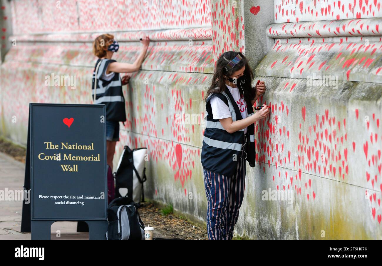 (210401) -- LONDRES, 1 de abril de 2021 (Xinhua) -- los voluntarios pintan corazones rojos representando a las víctimas que murieron de COVID-19 en el Muro Conmemorativo Nacional del COVID en las afueras del Hospital St Thomas en Londres, Gran Bretaña, el 31 de marzo de 2021. Los familiares y voluntarios que han sido afligidos están pintando corazones a lo largo de una pared de media milla frente a las Casas del Parlamento en Londres en recuerdo de los que murieron de COVID-19. Otras 4.052 personas en Gran Bretaña resultaron positivas para COVID-19, con lo que el número total de casos de coronavirus en el país asciende a 4.345.788, según cifras oficiales publicadas por el miércoles Foto de stock