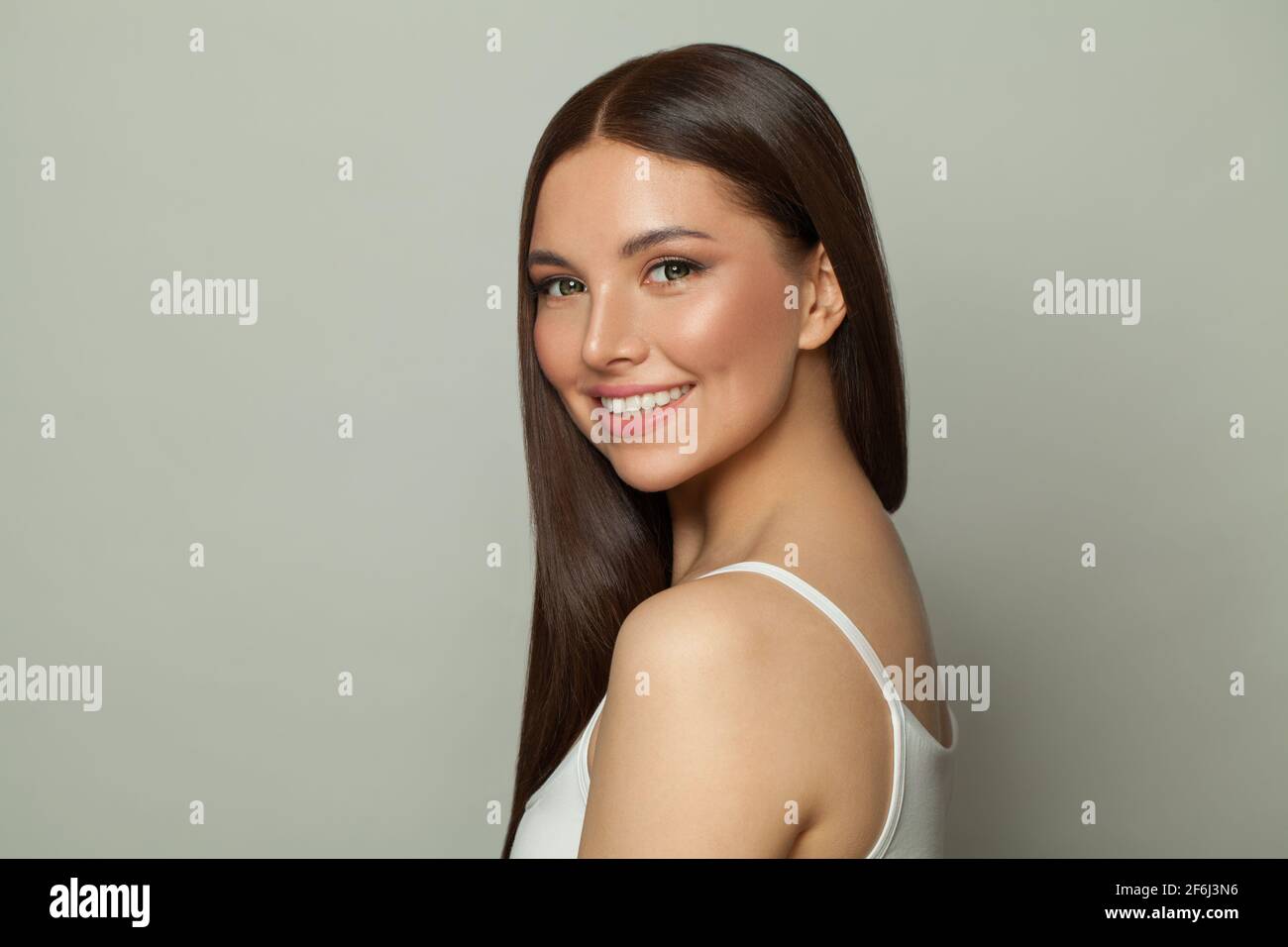 Joven hermosa morena modelo mujer con piel clara y larga cabello recto sano  sonriendo sobre fondo blanco Fotografía de stock - Alamy