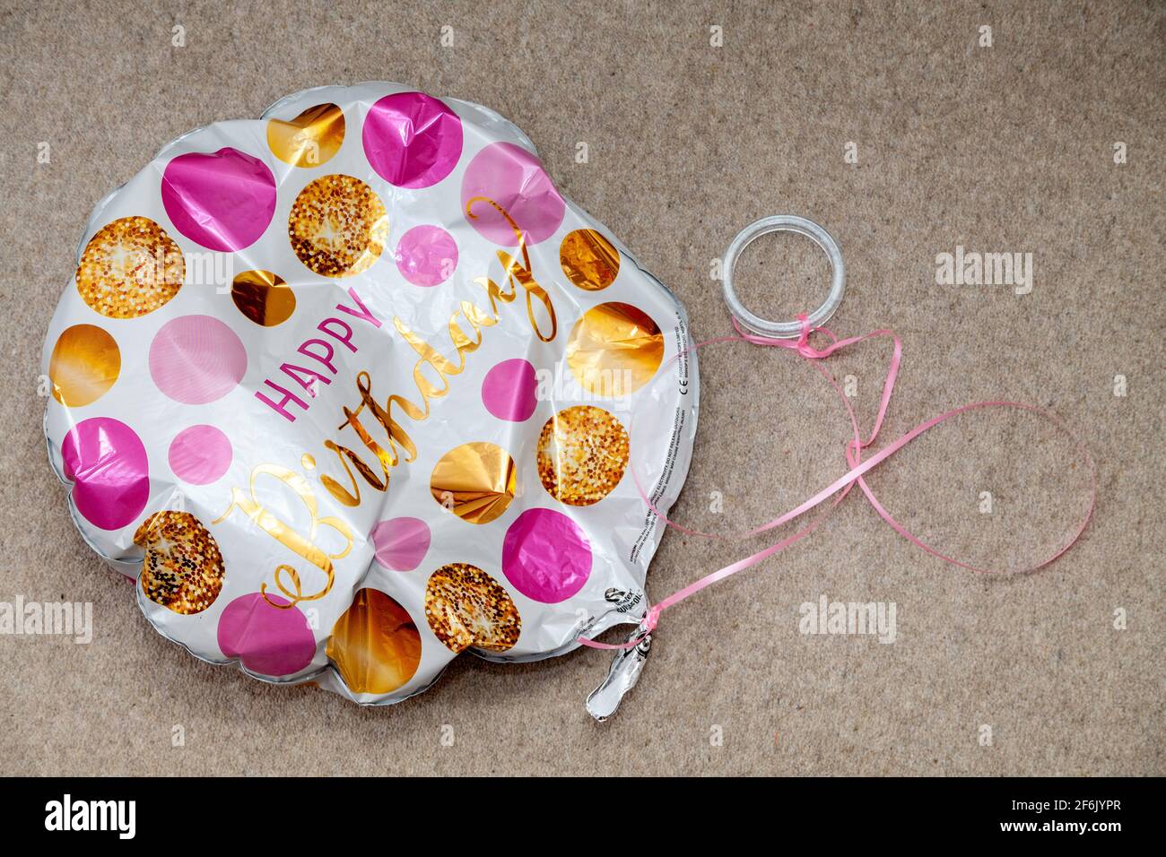 Un globo de feliz cumpleaños desinflado en el suelo Foto de stock