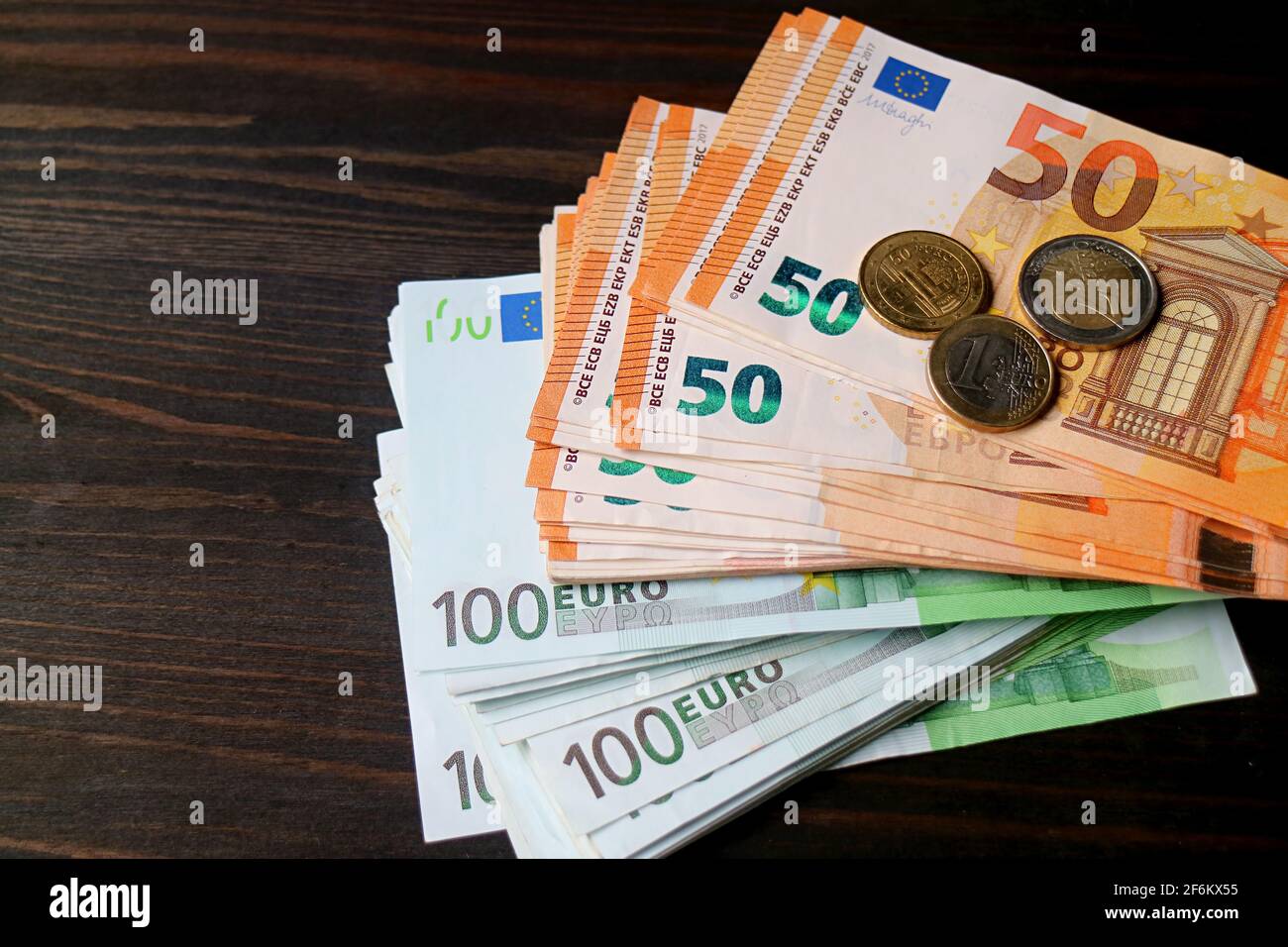 Paquete de billetes y monedas en euros en madera marrón oscuro Fondo con  espacio de copia Fotografía de stock - Alamy