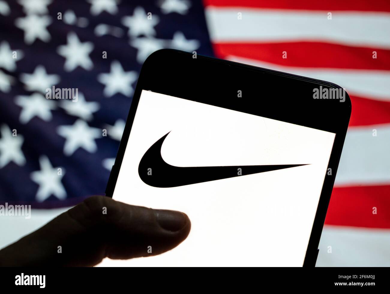 En esta ilustración de la foto, el logotipo de la Marca de ropa deportiva  multinacional estadounidense Nike se ve en un dispositivo móvil Android con  la bandera de Estados Unidos de América (
