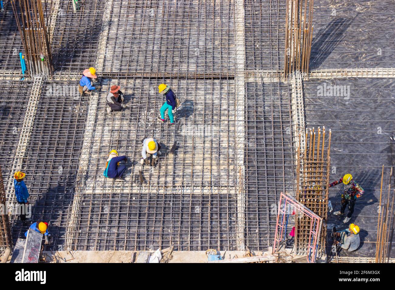 Trabajadores de la construcción que fabrican barras de refuerzo de barras de acero grandes en el sitio de construcción del área de construcción. Foto de stock