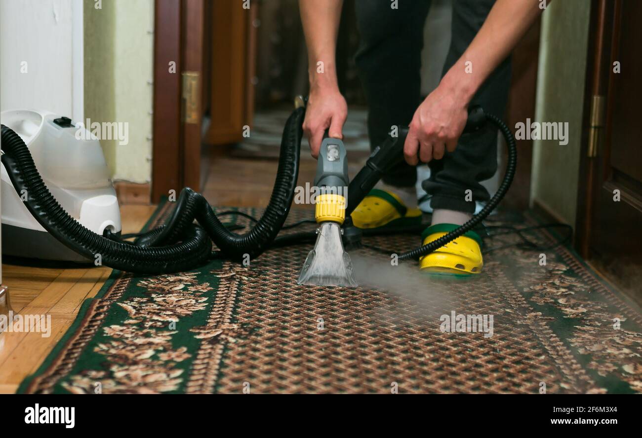 el proceso de limpieza de la alfombra con una aspiradora con filtro de agua.  una mujer recoge los restos de espuma limpiadora de la superficie sucia de  la alfombra 13699786 Foto de