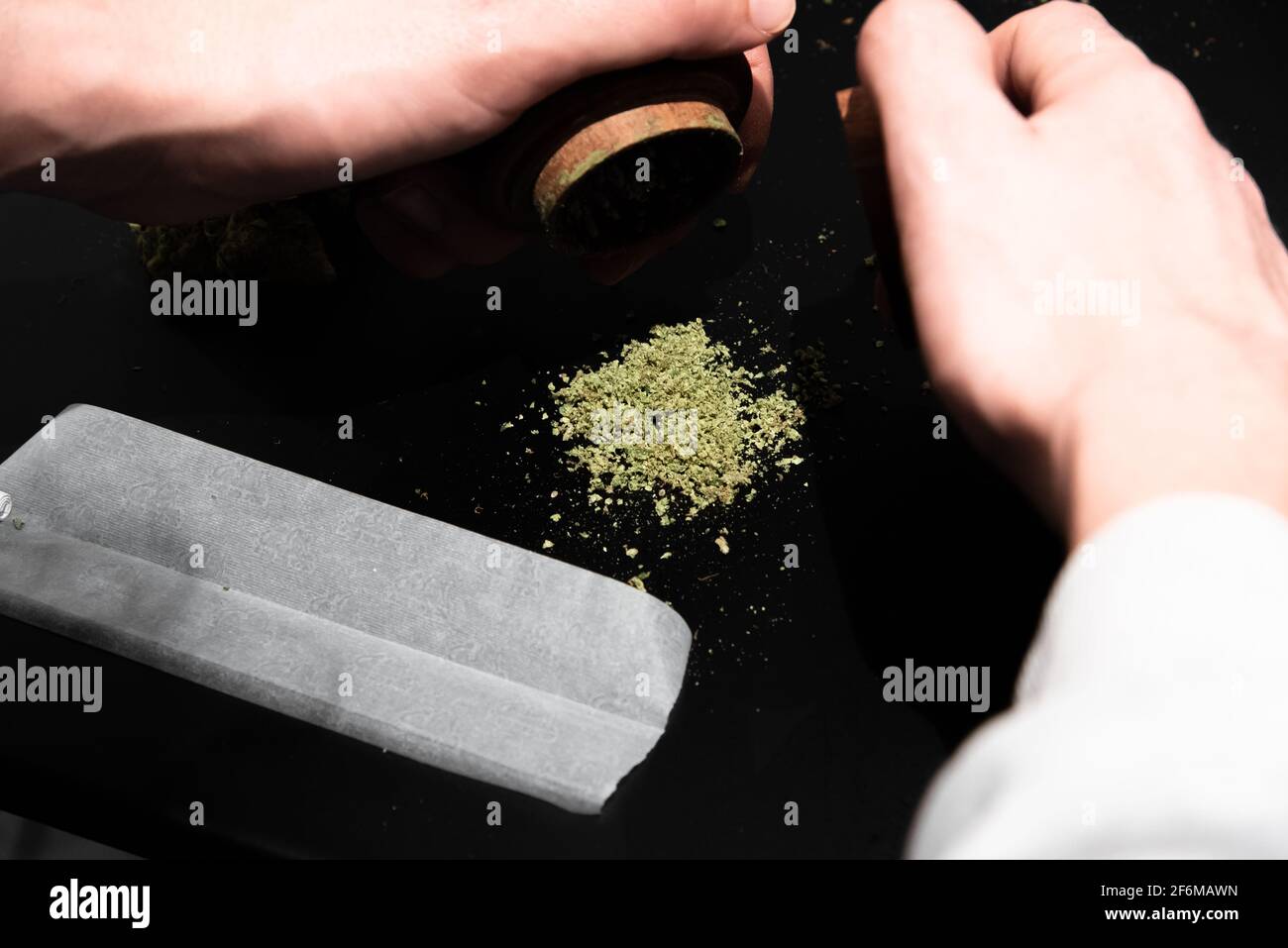 Cannabis en un molinillo y otros utensilios para fumar en un tabla Foto de stock