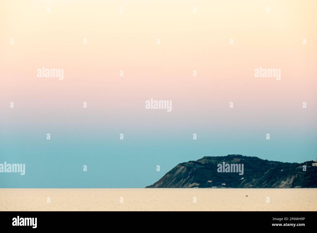 El promontorio de Gabicce que se adentra en el mar Adriático durante una tranquila puesta de sol, sin nubes en el cielo, colores brillantes Foto de stock