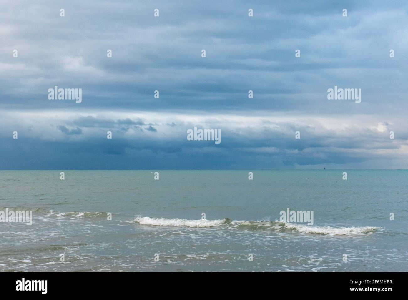 Agua de mar con olas y cielo nublado durante un mal día meteorológico Foto de stock