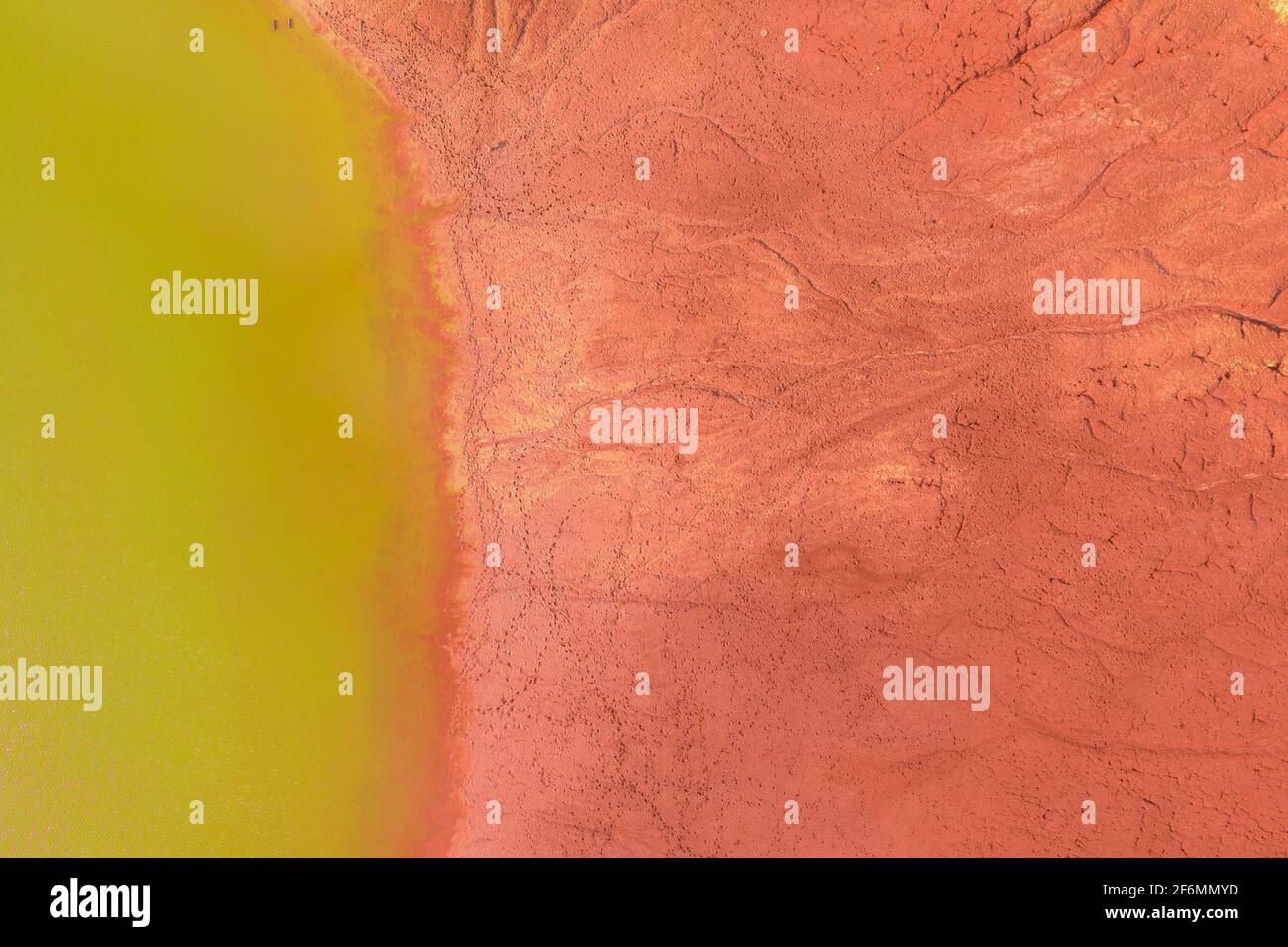 Neszmély, Hungría - Vista aérea de la superficie de barro rojo sequía con lago de color verde. Foto de stock