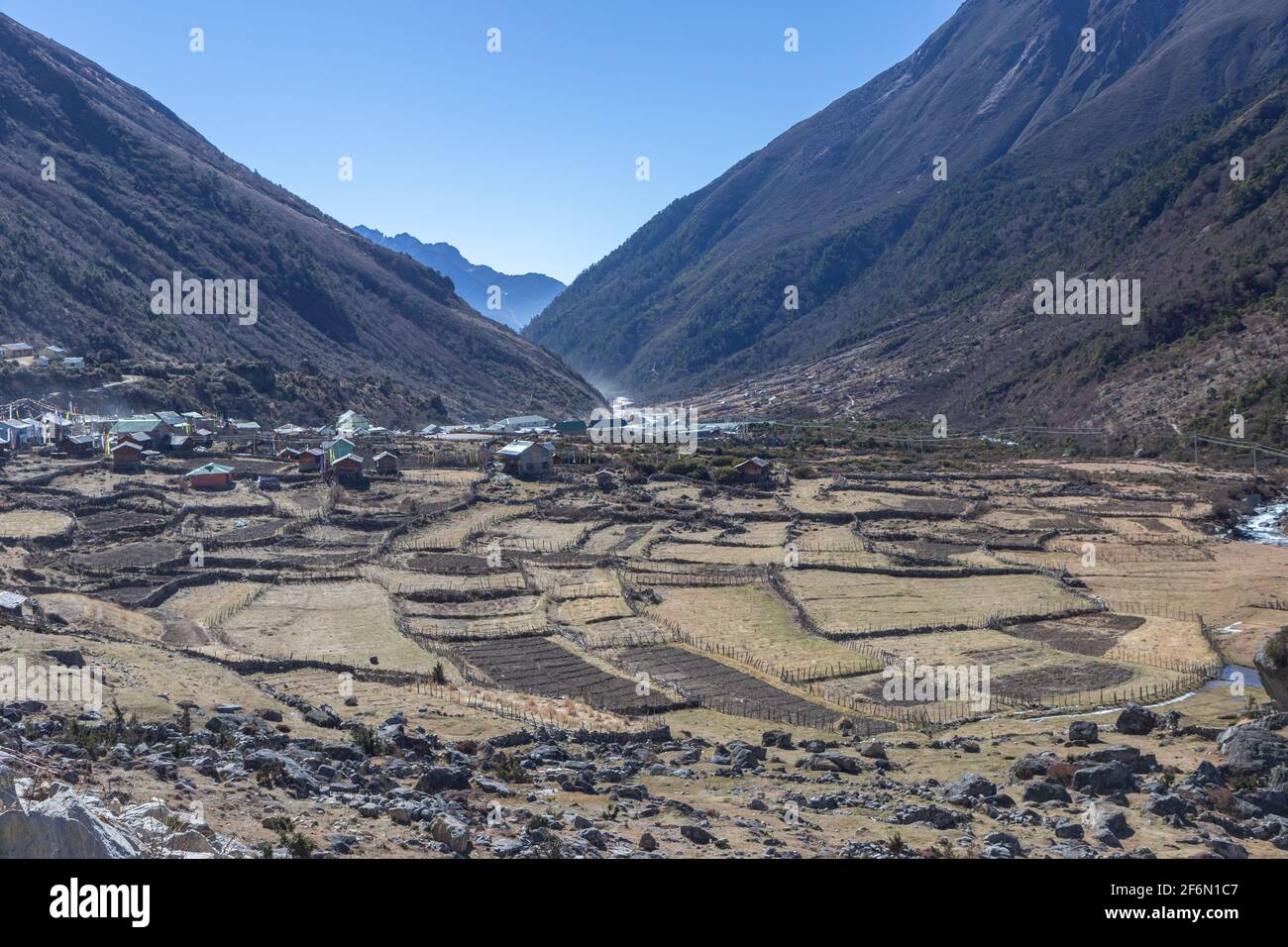 Pequeño pueblo situado en un valle con terrazas en primer plano y cielo azul claro en el fondo En Sikkim India el 22 de noviembre de 2016 Foto de stock