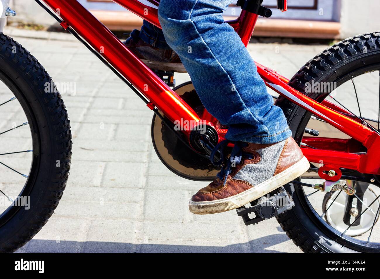 El pie de un niño en las zapatillas de deporte gira el pedal de la bicicleta.  Montar en bicicleta para niños Fotografía de stock - Alamy