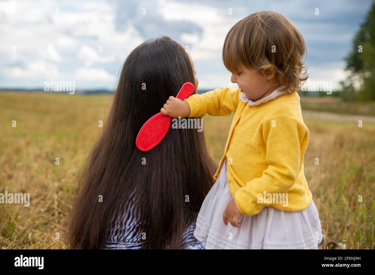 adorable niña peinadora peinando el cabello de su mamá al aire libre en un  día soleado Fotografía de stock - Alamy
