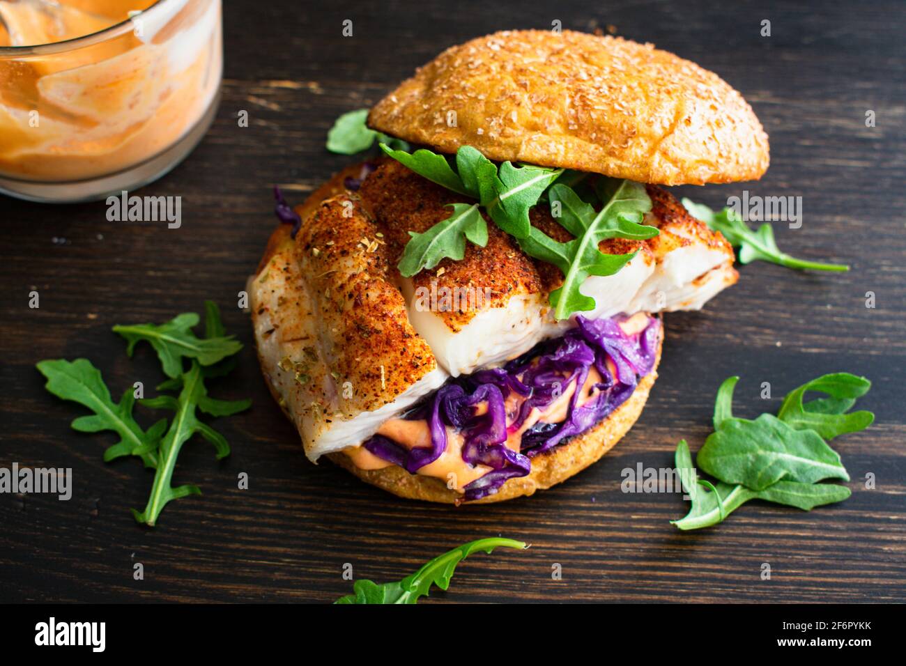 Hamburguesa de pescado ennegrecido y Sriracha Mayo: Un sandwich de pescado de halibut con col roja y arúgula en un bollo entero de brioche de trigo Foto de stock