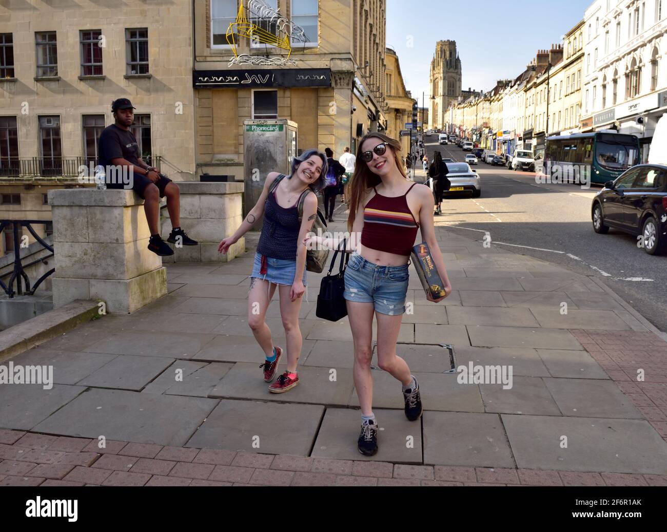 Dos mujeres jóvenes disfrutando del sol y la libertad Bristol Park Calle después de Reino Unido covid bloqueo aliviado Foto de stock