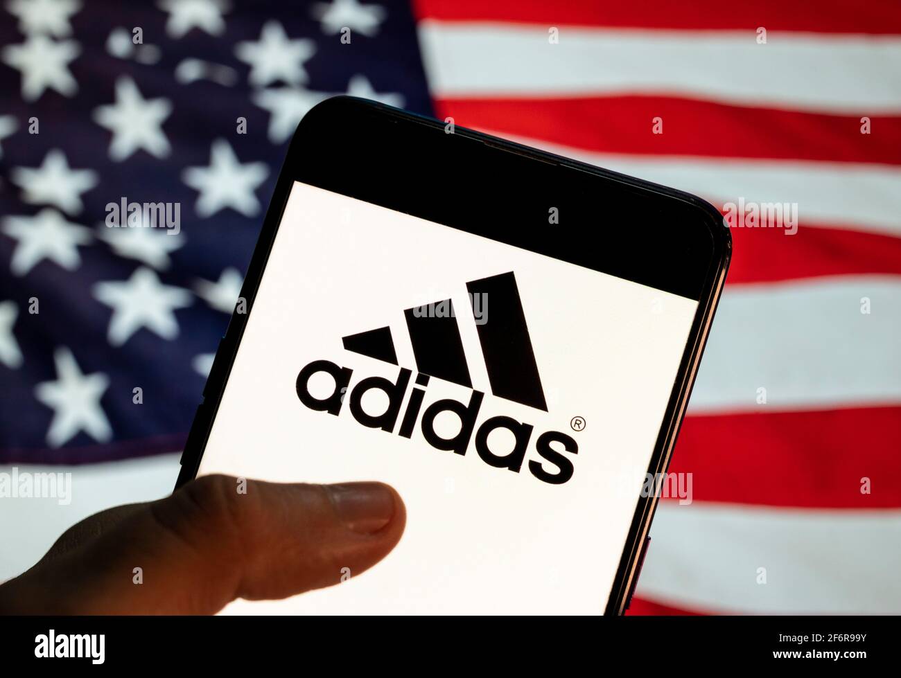 En esta ilustración de la foto, el logotipo de la Marca multinacional  alemana de ropa deportiva Adidas se ve en un dispositivo móvil Android con  la bandera de Estados Unidos de América (