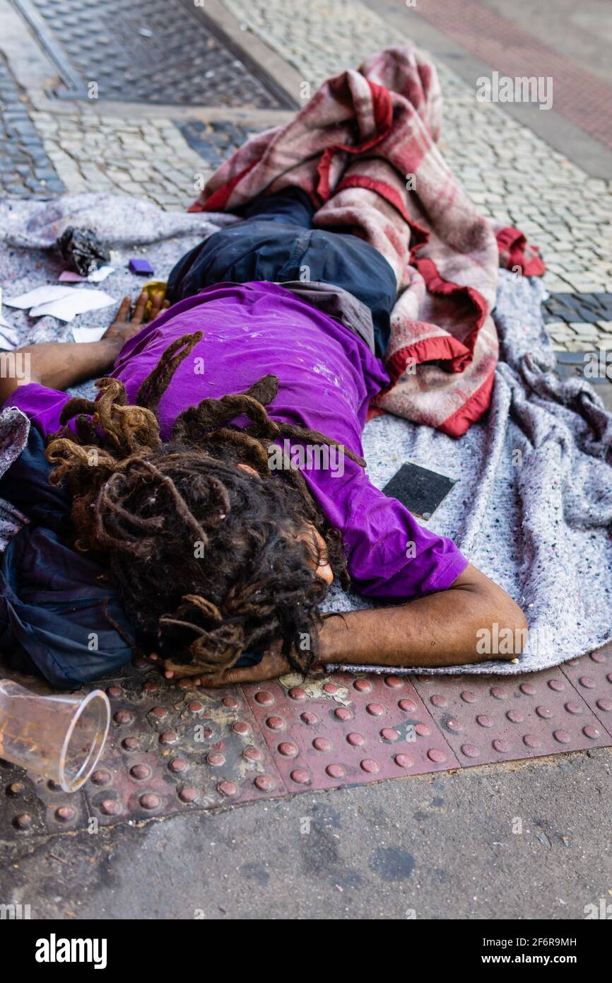 Drogadicto brasileño sin hogar durmiendo en la acera. Llevar ropa sucia y  temlocks. Espejo de cocaína en el lado Fotografía de stock - Alamy