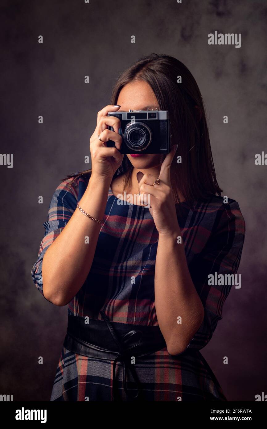 La fotógrafa chica toma fotos con una cámara antigua, fotografía de estudio  sobre un fondo gris Fotografía de stock - Alamy