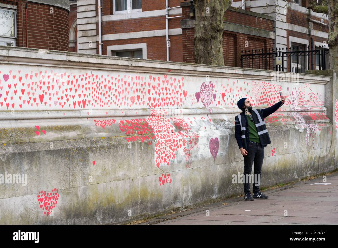 Un hombre toma un selfu en el muro nacional de covidos en el banco sur de Londres Embankment , Inglaterra, Reino Unido Foto de stock