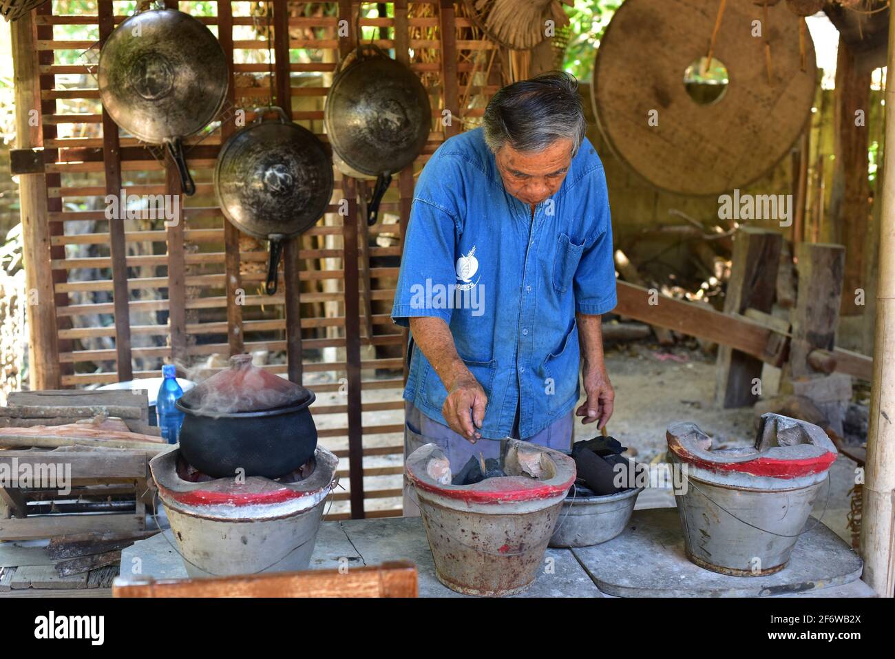 Chiang Mai, hombre encendiendo el fuego para cocinar en una casa tradicional. Tailandia. Foto de stock