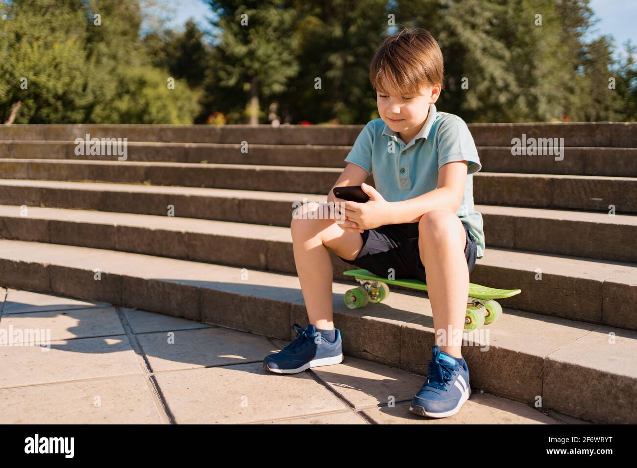 sentado en las escaleras con un smartphone en la mano y. penny board viendo videos divertidos Fotografía de stock - Alamy
