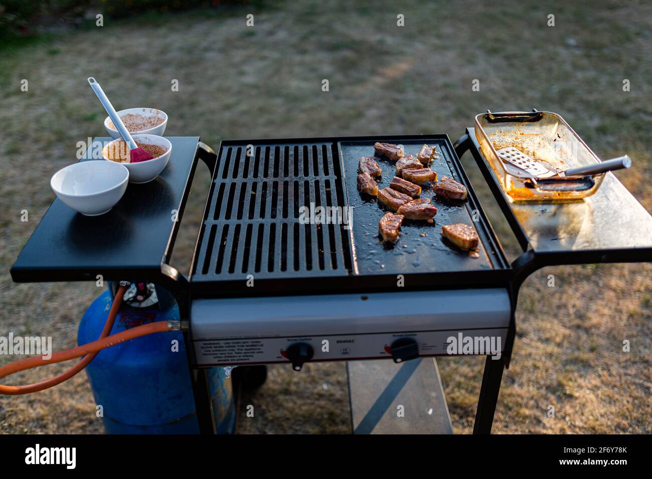una barbacoa de gas tradicional con una selección de carnes cocinadas en el sol de verano Foto de stock