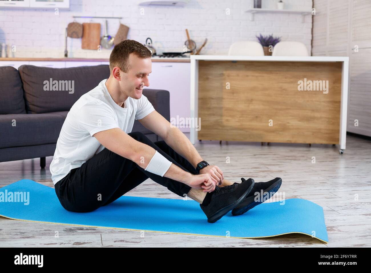 Un joven se va a practicar deportes en casa, ata los cordones de las  zapatillas de deporte antes de entrenar. Estilo de vida saludable  Fotografía de stock - Alamy