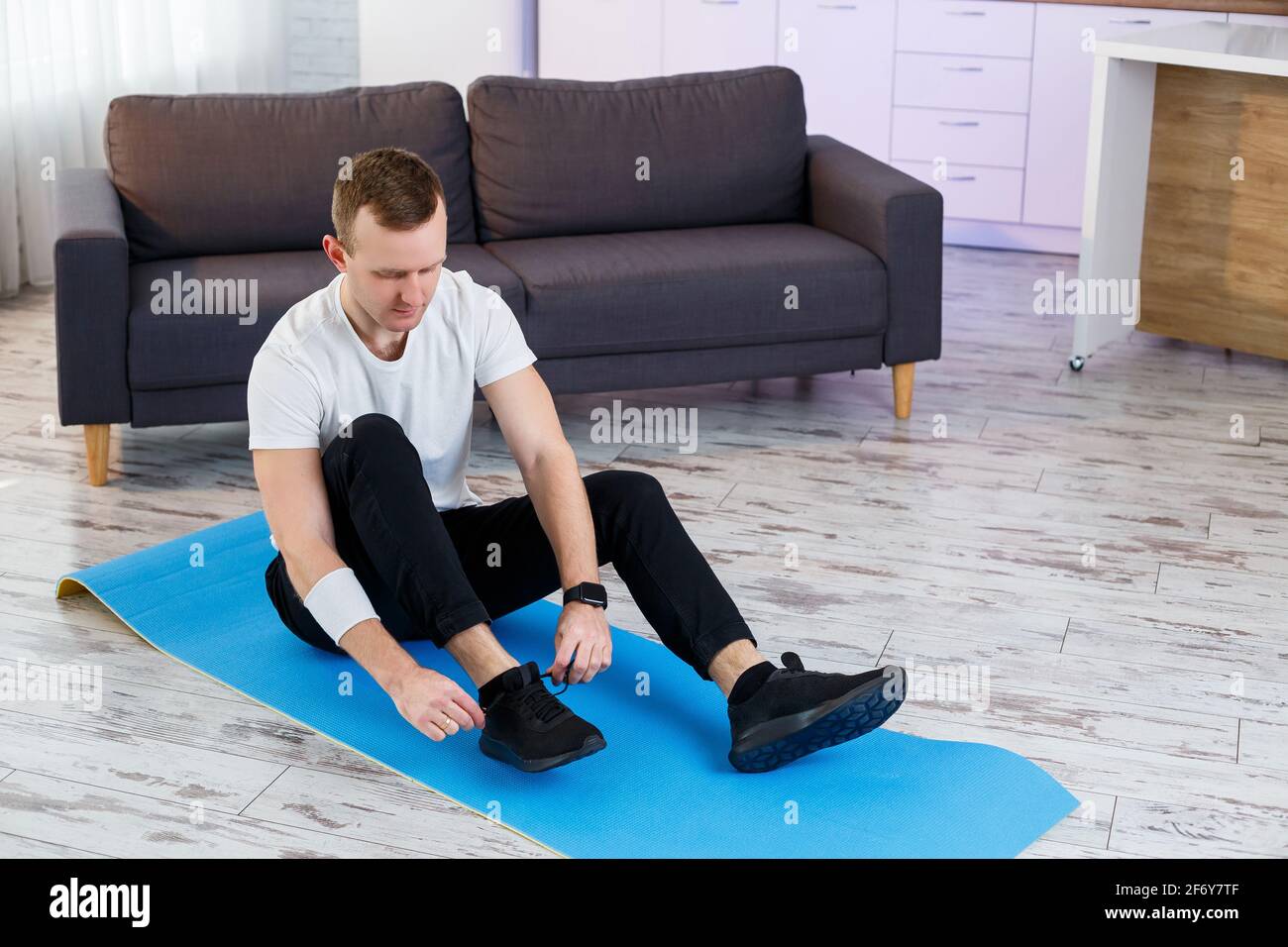 Un joven se va a practicar deportes en casa, ata los cordones de las  zapatillas de deporte antes de entrenar. Estilo de vida saludable  Fotografía de stock - Alamy