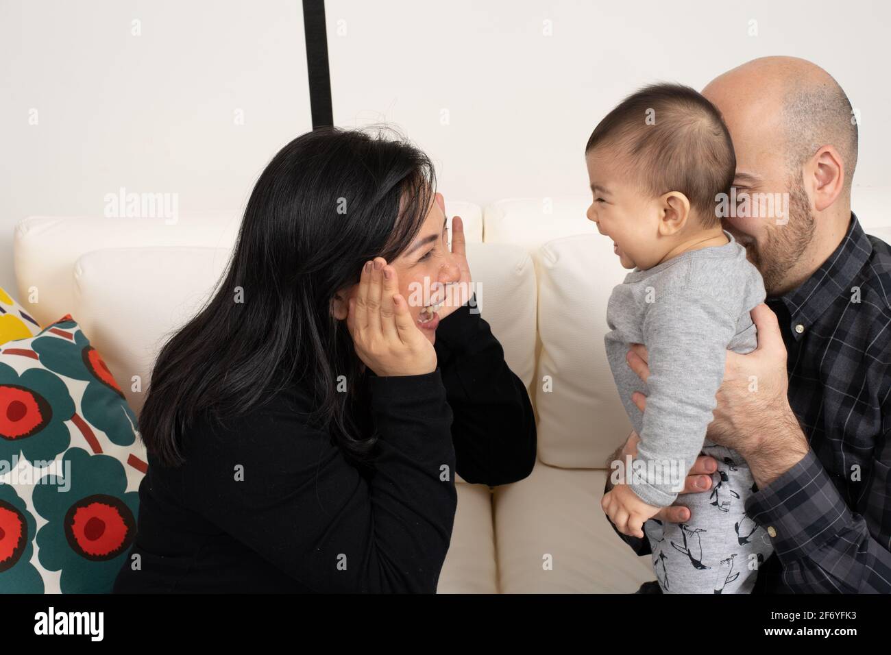 Niño de seis meses de edad PEEK un juego de tabú con madre y padre Foto de stock