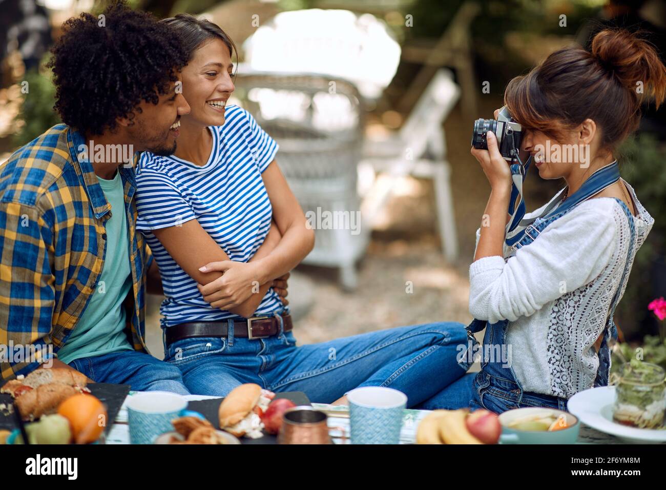 Una chica toma una foto de sus amigos en el patio trasero del bar en un tiempo hermoso. Tiempo de amistad de calidad juntos Foto de stock